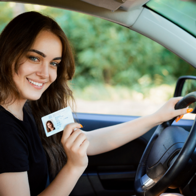 girl holding drivers license in her car
