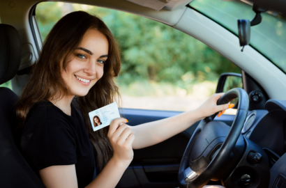 girl holding drivers license in her car