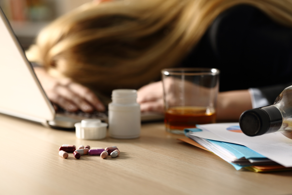 woman mixing pills and medications with alcohol while working