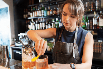 Lady bartender making speciality drink at the bar