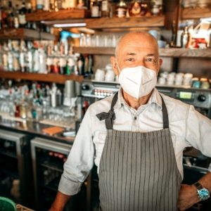 bar owner with mask behind the bar