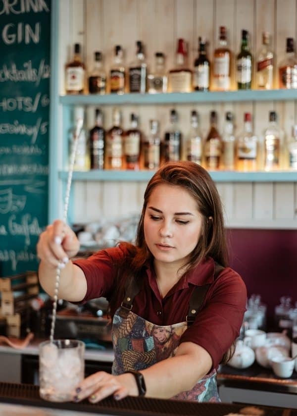 female bartender behind the bar mixing with a tall stir stick