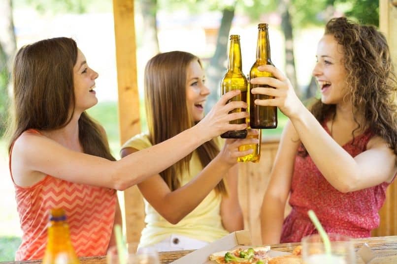 young girls cheers while drinking beers