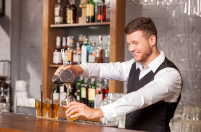 Attractive male bartender is making cocktail in bar