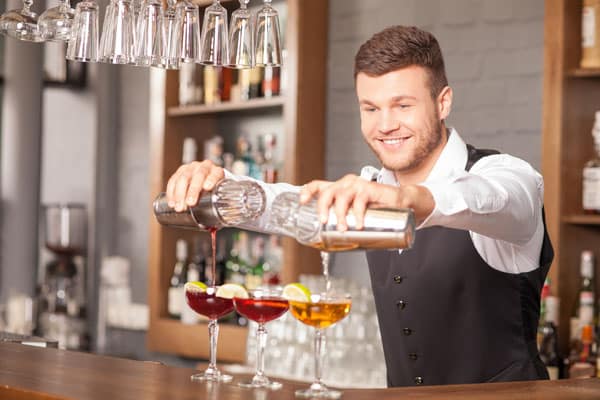 Attractive young bartender is making drinks in pub