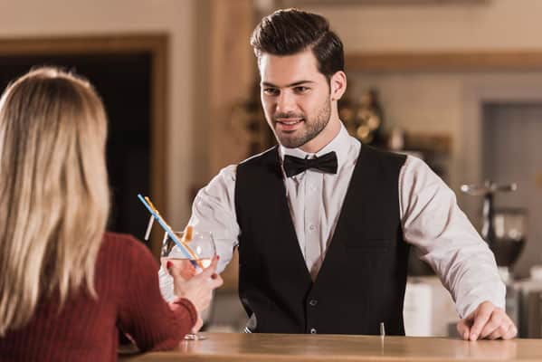 handsome bartender giving cocktail to woman at the bar