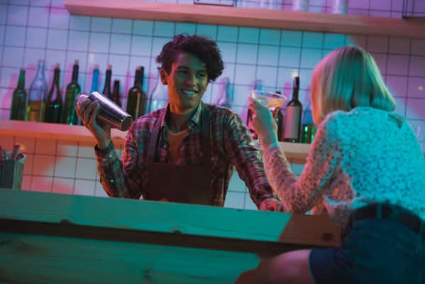 smiling barman with shaker talking to female