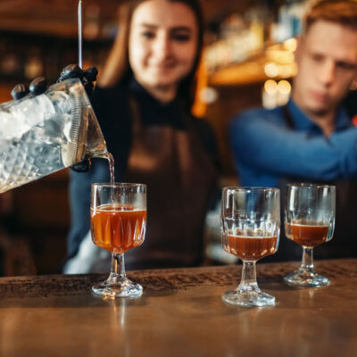 Bartending is a popular profession, Male and female bartender at the bar counter. Alcohol drink preparation. Two barmans working in pub