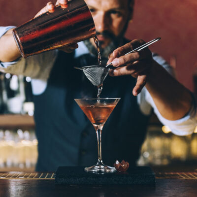 Barman is making cocktail at night club, bartender skills