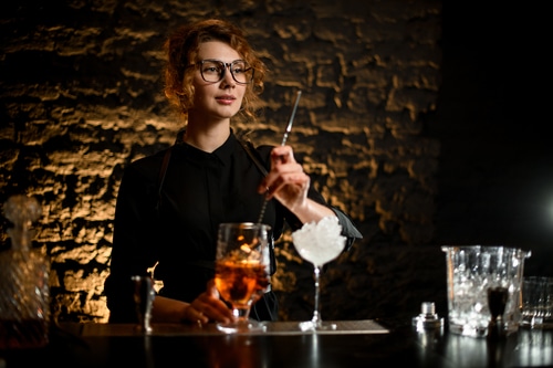 young attractive woman mix cocktail in glass with bar spoon, Bartending class