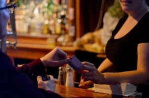 server gives drink coaster to patron