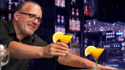 bartender serves a customer a drink in a martini glass
