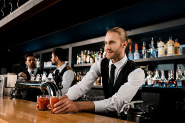 handsome bartender serving drinks in glasses at a bar