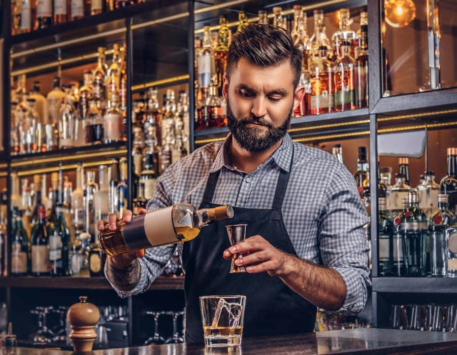 handsome bartender pours shot behind the bar getting his rbs certification
