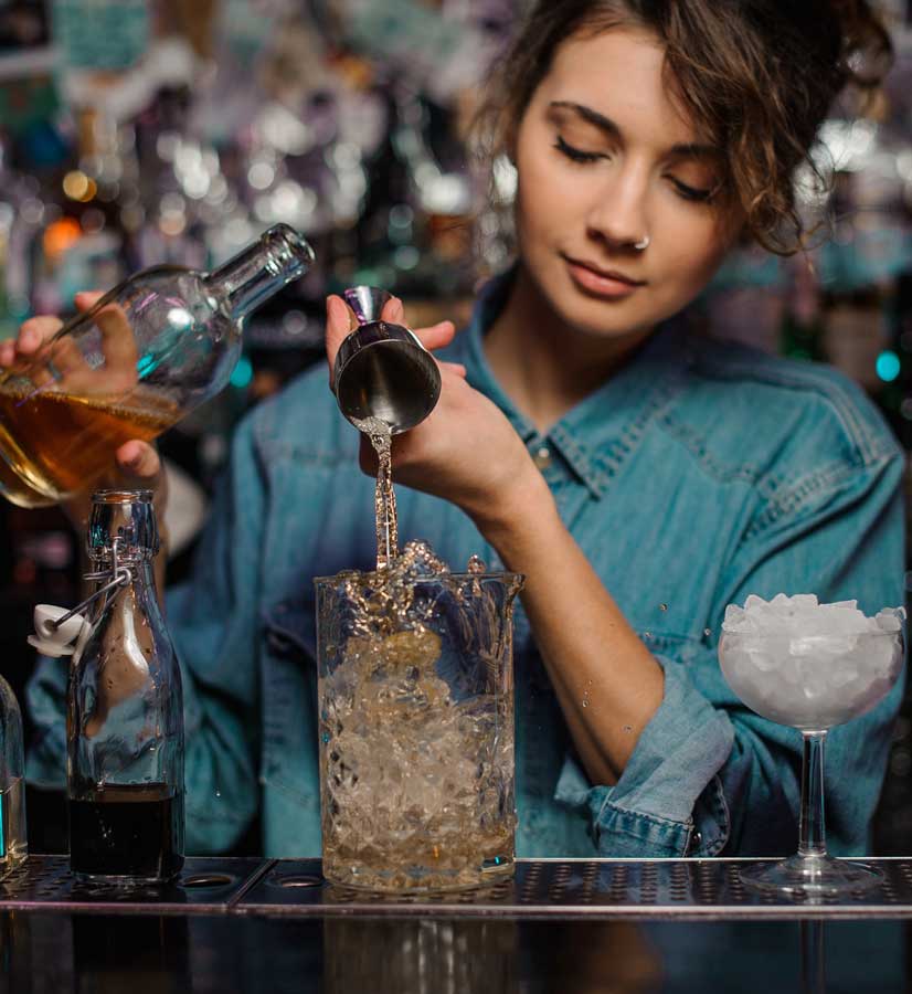 female bartender pouring to the measuring shot glass