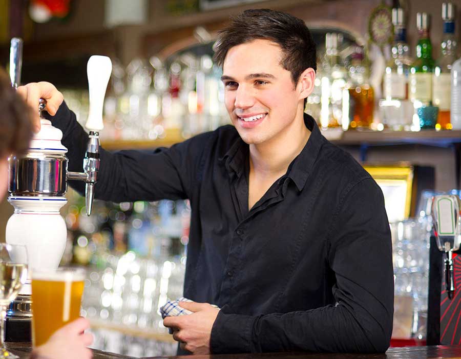 cute bartender leans on tap behind the bar