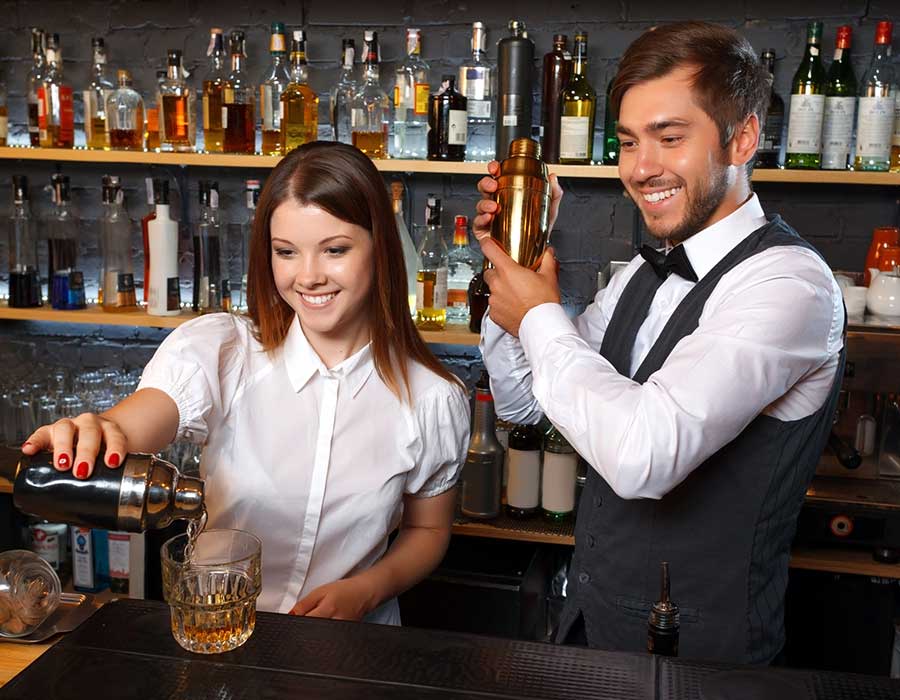 male bartender and waitress in white behind the bar