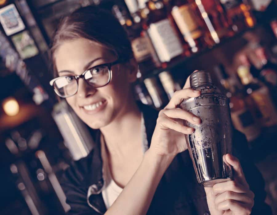 pretty bartender with glasses on and shaking a drink