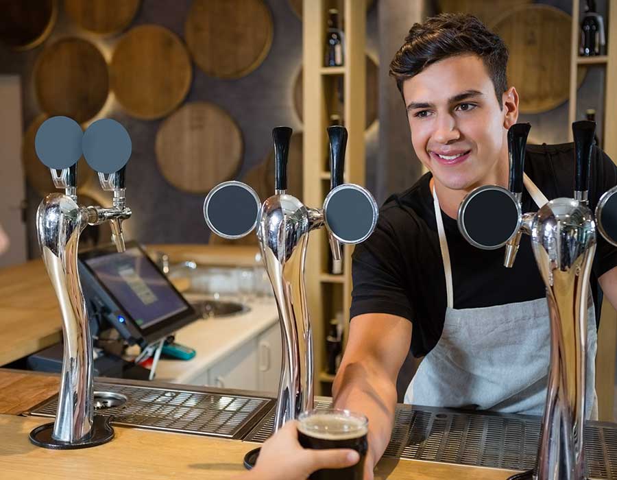 young cute smiling bartender serving beer glass