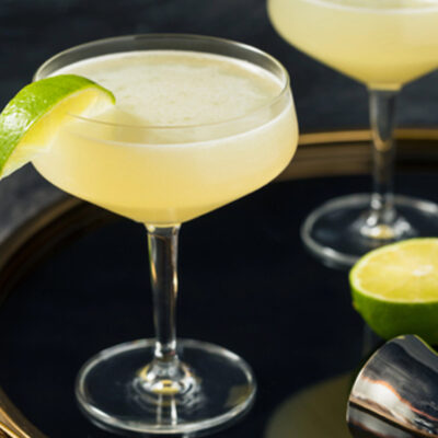 A chilled gimlet cocktail in a coupe glass garnished with a fresh lime wedge.